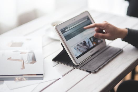 A person using a tablet on a sleek desktop, showcasing a contemporary workspace setting.