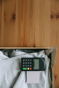 Close-up of a card payment terminal on top of gray clothing in a wooden box, indoors.