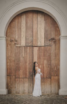 A bride in a wedding dress stands gracefully by a large wooden church door in Cali, Colombia.